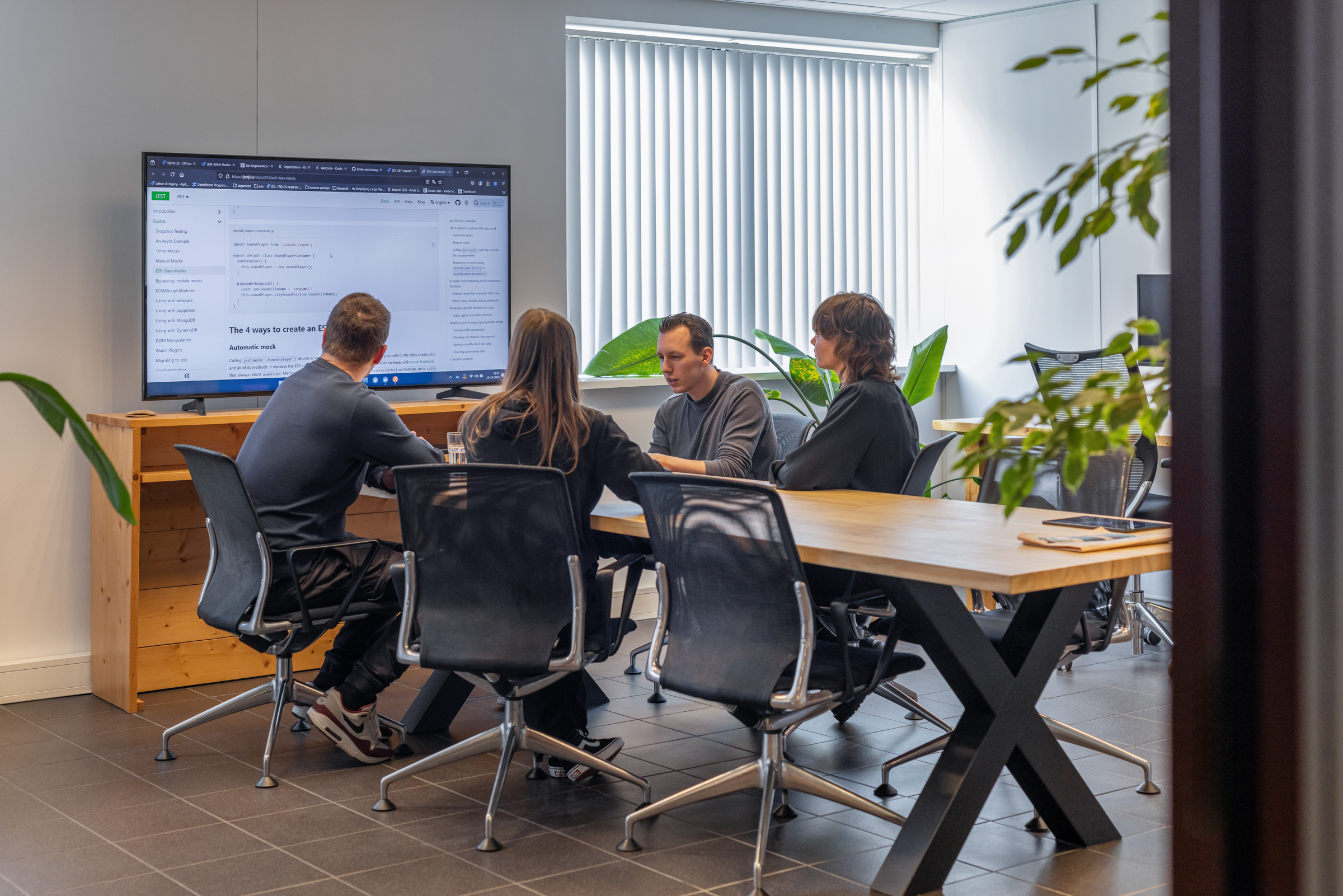 groep dames en heren in overleg in een vergaderruimte voor een groot scherm