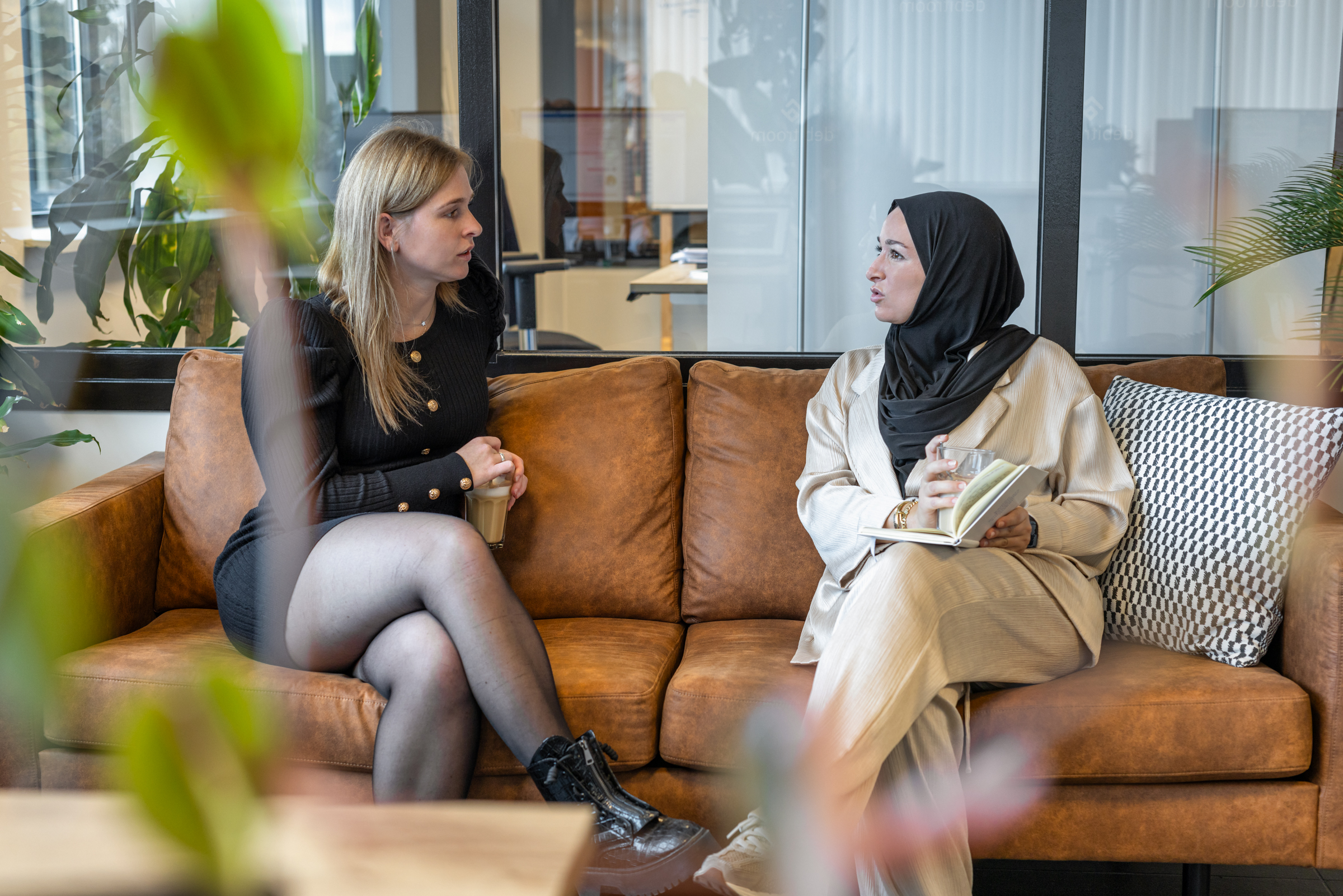 twee vrouwen in overleg zittend op bruine bank